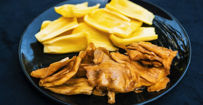 Close-up comparison of fresh jackfruit pieces and DoGood organic dried jackfruit slices served on a black plate