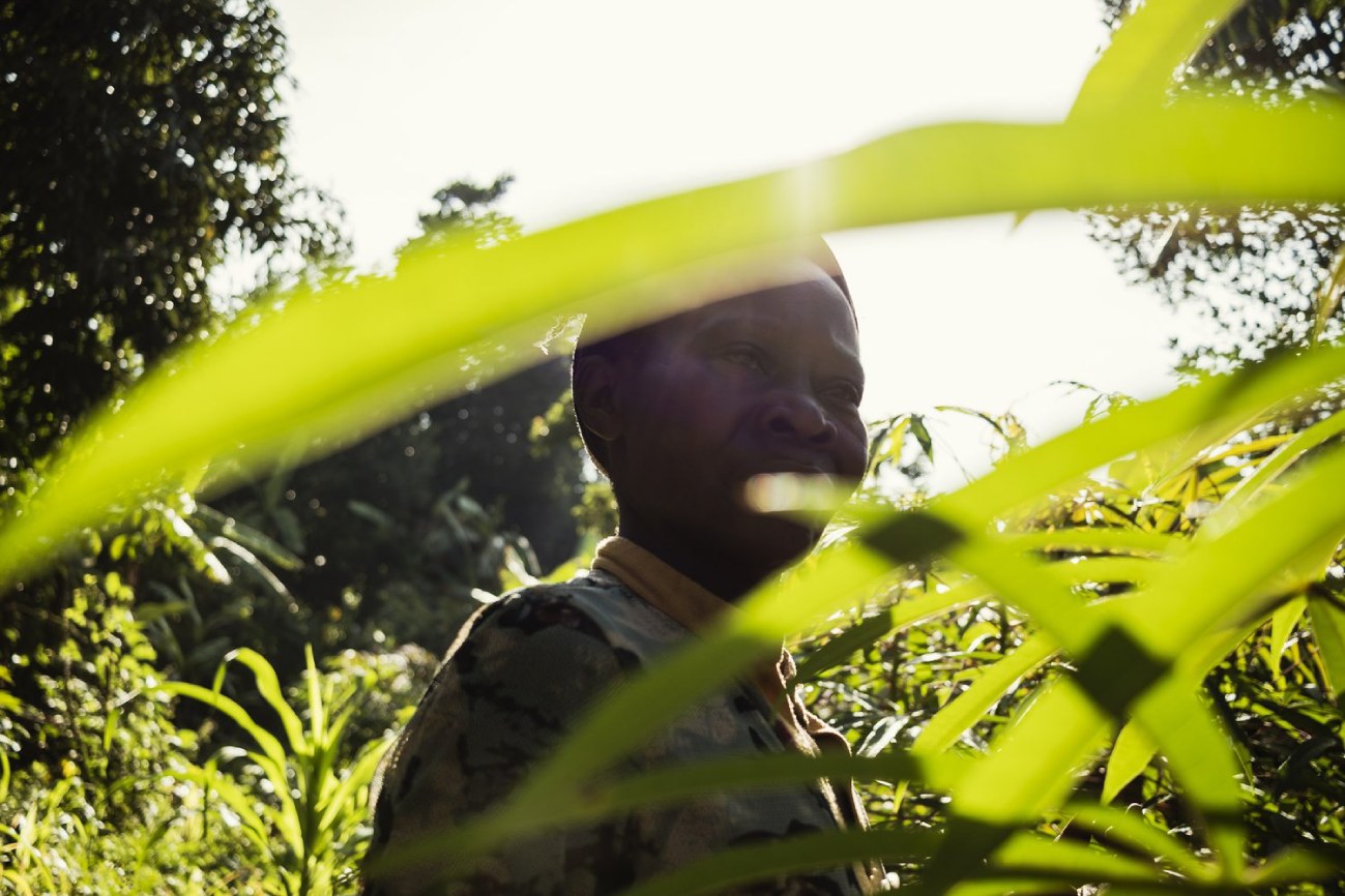 Ugandan farmer working in lush green fields with sunlight filtering through leaves – supporting DoGood Earth’s sustainable organic farming practices